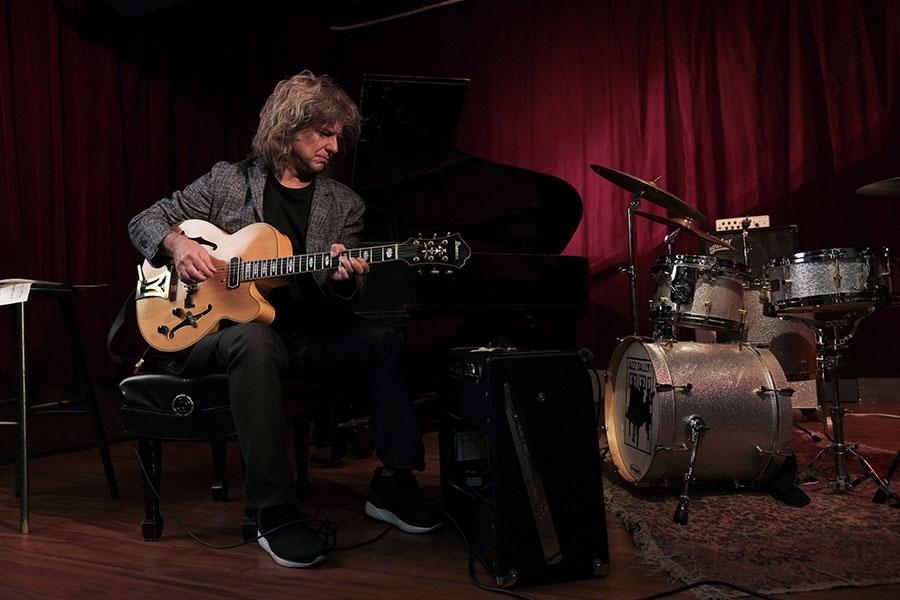 Pat Metheny sits as he plays guitar