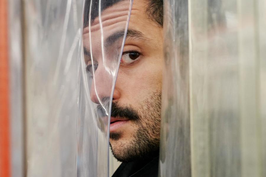 H Sinno poses behind plastic curtains