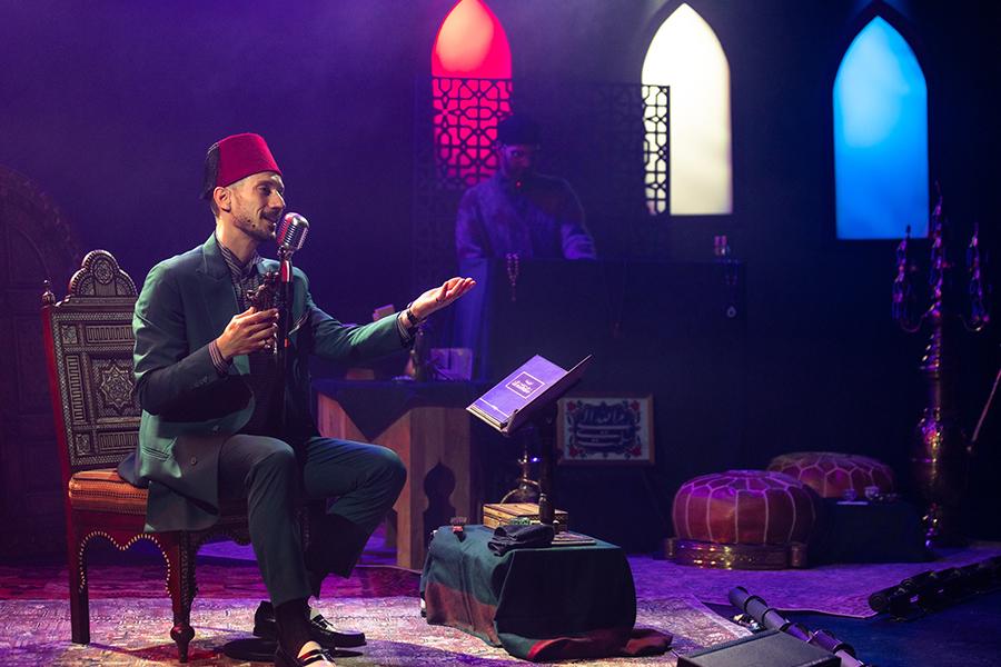 Man sits on stage speaking into microphone